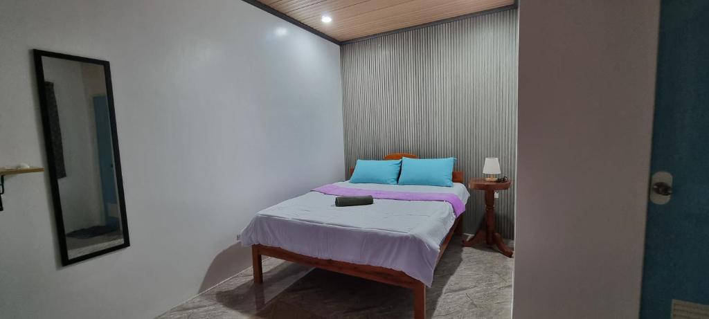 um pequeno quarto com uma cama com almofadas roxas e azuis em Mollucan Residence # 2 em Moalboal