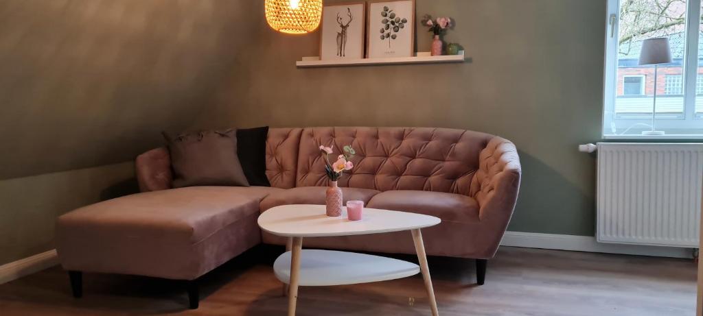 - un salon avec un canapé brun et une table dans l'établissement Ferienwohnung am Bibelgarten Sophia, à Werlte