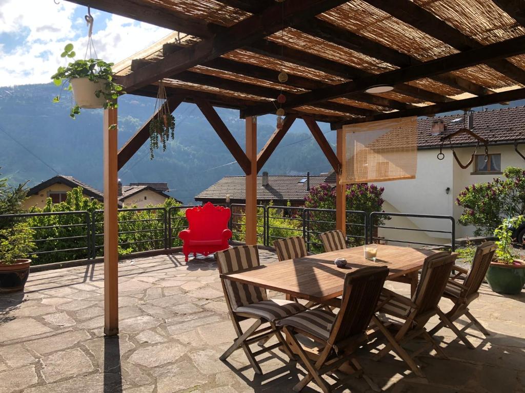 a wooden table and chairs on a patio with a pergola at Chambre sur terrasse in Nendaz