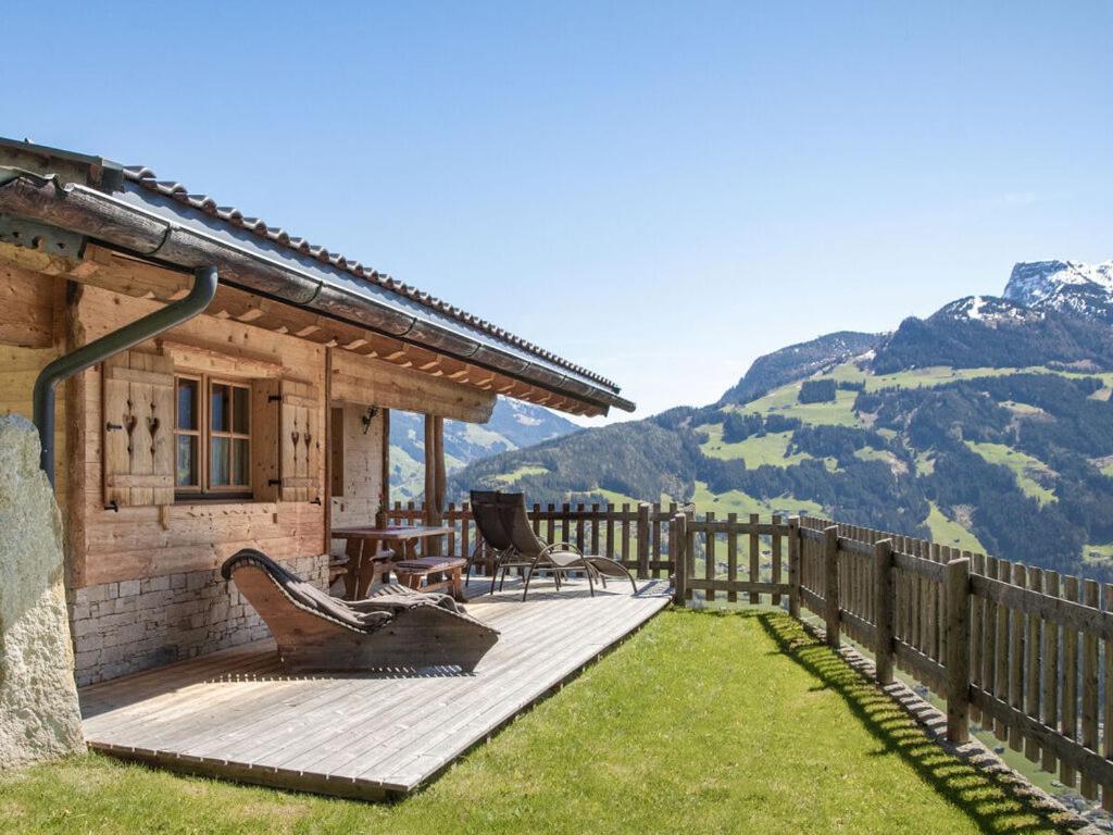 a house with a wooden deck with mountains in the background at Wellness Chalet Bergschlössl in Hippach