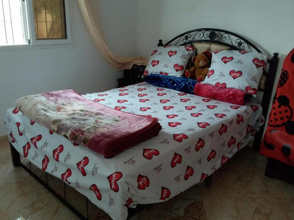 a bed with a teddy bear laying on it at Charmante maison de campagne in Temara