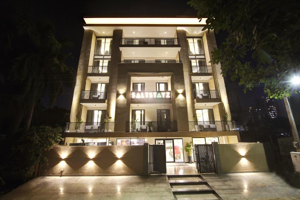 un edificio alto con luces delante de él por la noche en Saltstayz Amara - Near MG Road and Sector 29, en Gurgaon