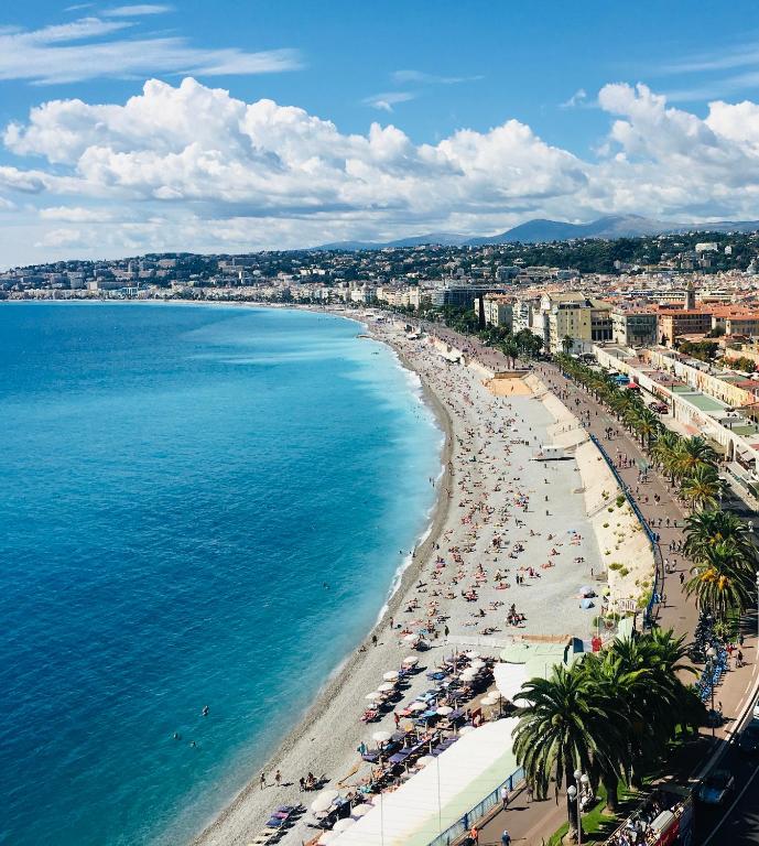 - une vue aérienne sur une plage avec des hommes et l'océan dans l'établissement Magnificent renovated apartment, 2 rooms of 45 m2, close tothe sea, top floor, terrace, à Nice
