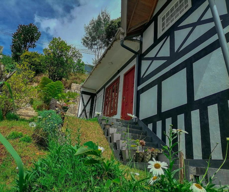 una casa con una puerta roja y algunas flores en Tea Bound Resort, en Nuwara Eliya