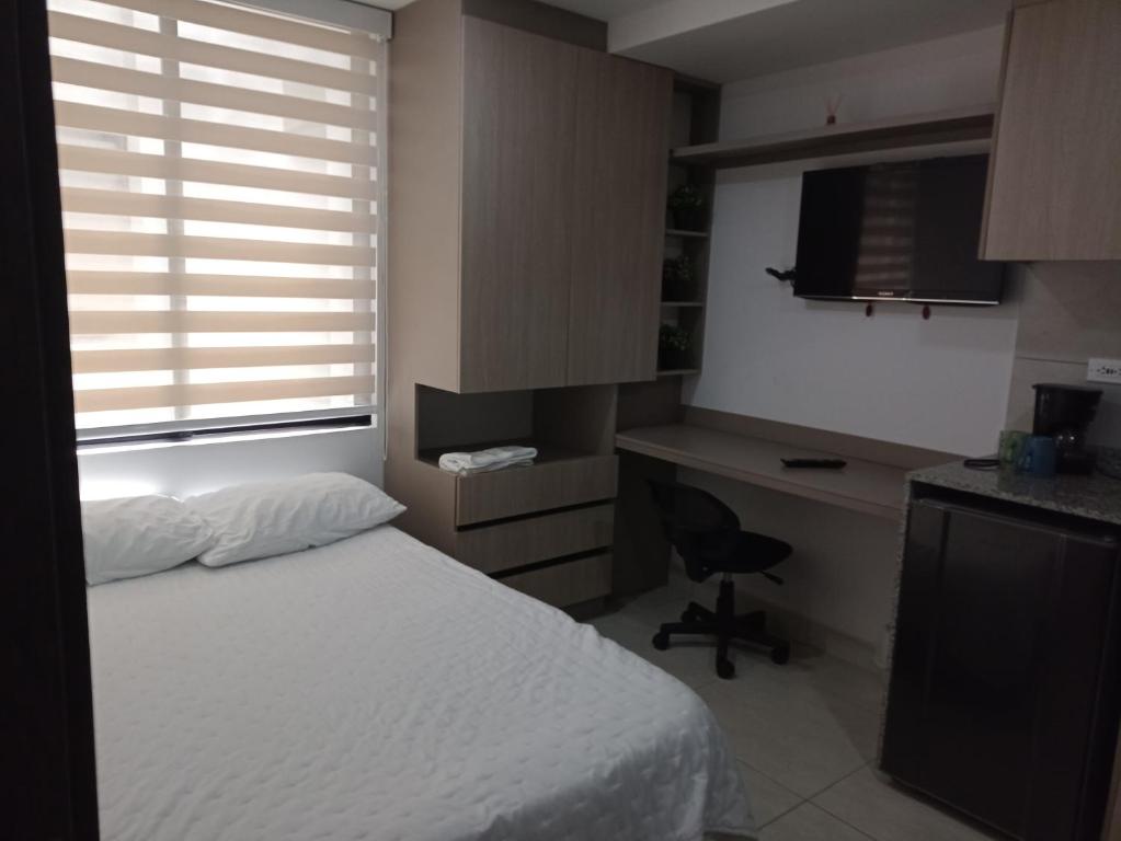 Cette chambre comprend un lit, un bureau et une télévision. dans l'établissement Apto en Zona Turística de Popayán, à Popayan