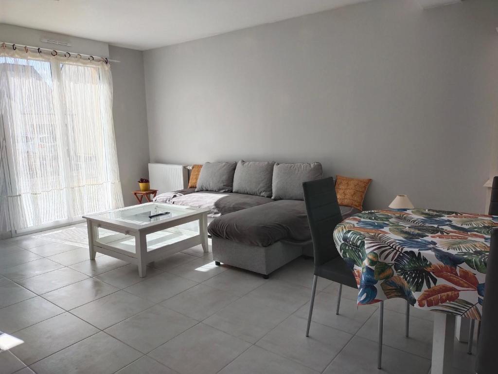a living room with a couch and a table at Le palmier nantais in Mouzeil