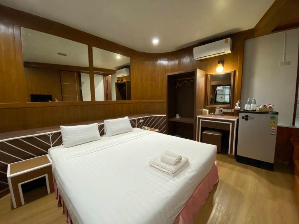 a bedroom with a large white bed and a kitchen at โรงแรม เพนท์เฮ้าส์ รีสอร์ท เบตง in Betong