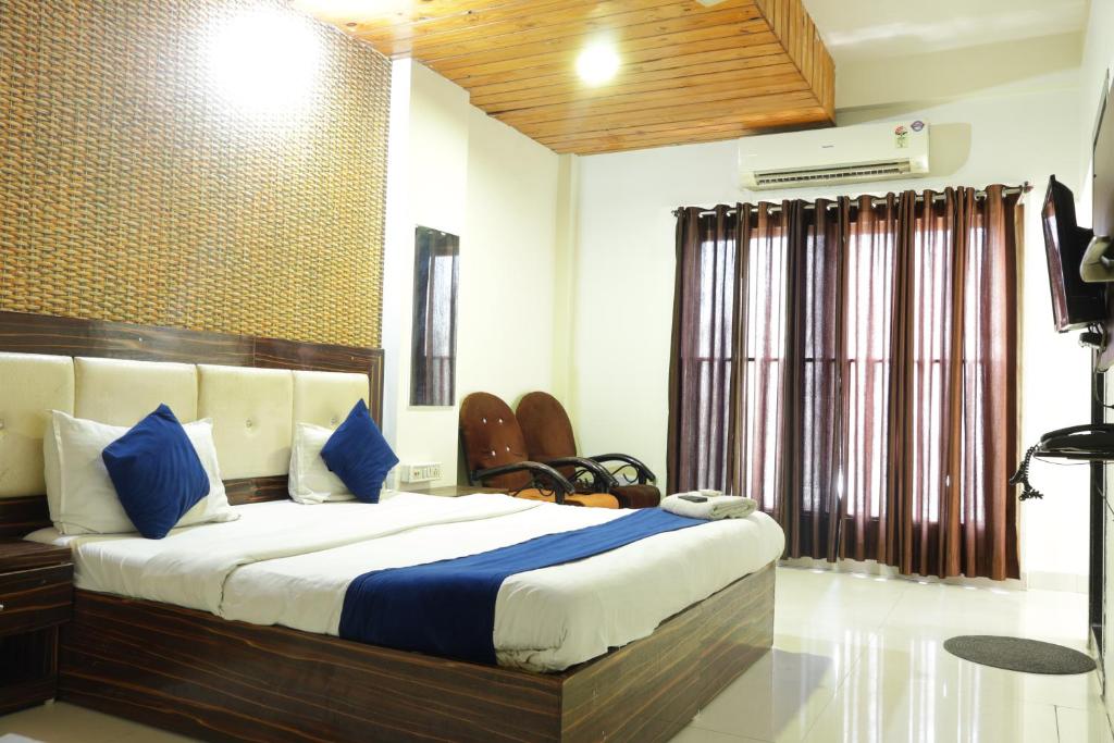 um quarto com uma cama grande e almofadas azuis em Hotel Kanchan Palace em Indore