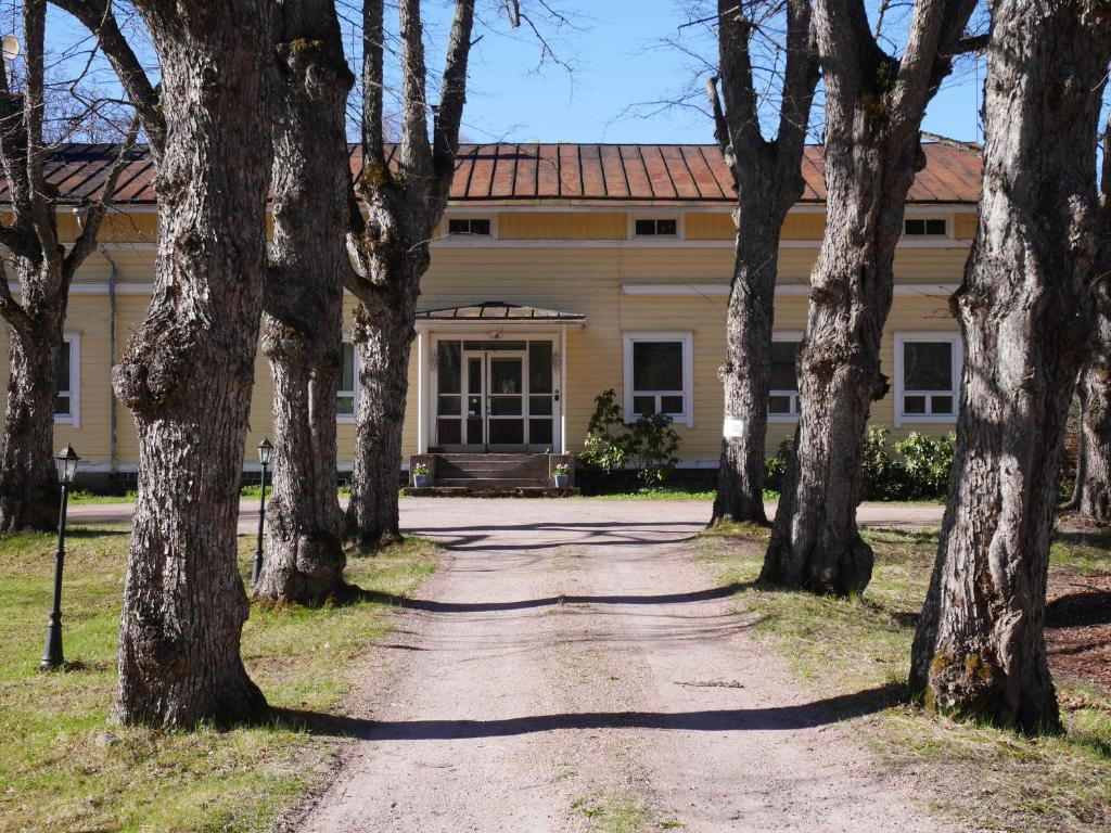 um edifício antigo com árvores em frente em Lindallén Guest House em Fiskars