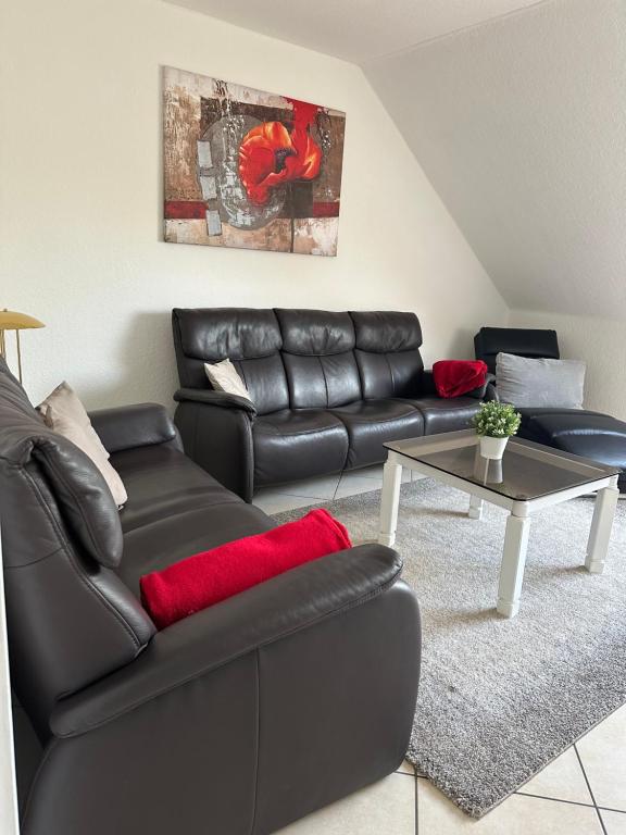 a living room with a black leather couch and a table at Aminas Ferienwohnung Bad Gandersheim 30/2 in Bad Gandersheim