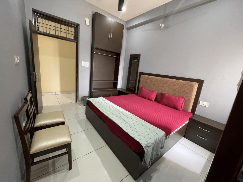 Schlafzimmer mit einem Bett mit roter Bettwäsche und einem Stuhl in der Unterkunft BLD Restaurant And Home Stay in Dehradun