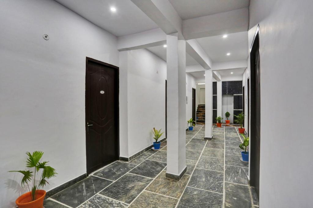 um corredor com vasos de plantas e uma porta preta em Collection O Hotel RBS em Lucknow