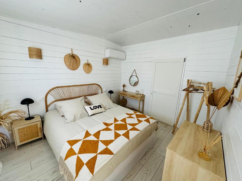una camera con un letto in una stanza con pareti bianche di Cabane le Flamant avec jardin, piscine chauffée et parking a Saintes-Maries-de-la-Mer