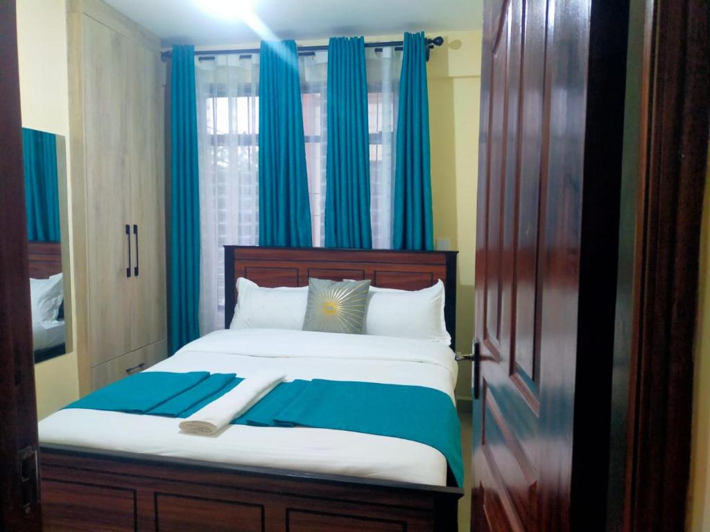 a bedroom with a large bed with blue curtains at Javic Home in Nakuru
