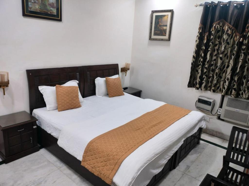een slaapkamer met een bed met witte lakens en kussens bij YANA B&B in New Delhi