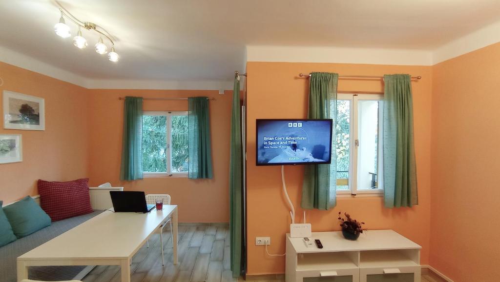 ein Wohnzimmer mit einem Sofa und einem TV an der Wand in der Unterkunft Bonrila Sun Apartman in Zamárdi