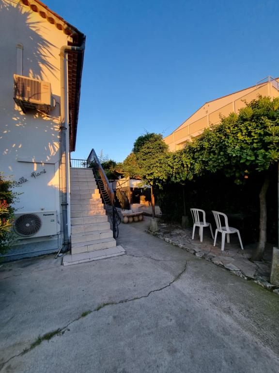un patio avec deux chaises et un escalier à côté d'un bâtiment dans l'établissement Villa Mané, à Antibes