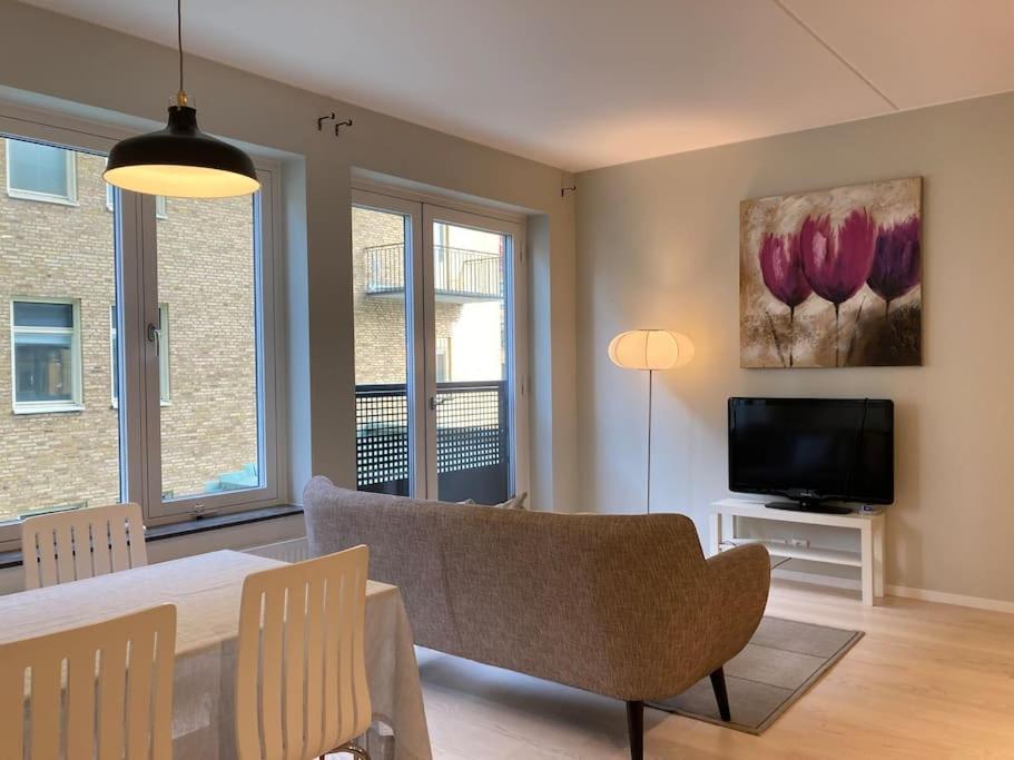 - un salon avec un canapé, une table et une télévision dans l'établissement PinkRose CityStay Järnvågen, à Göteborg