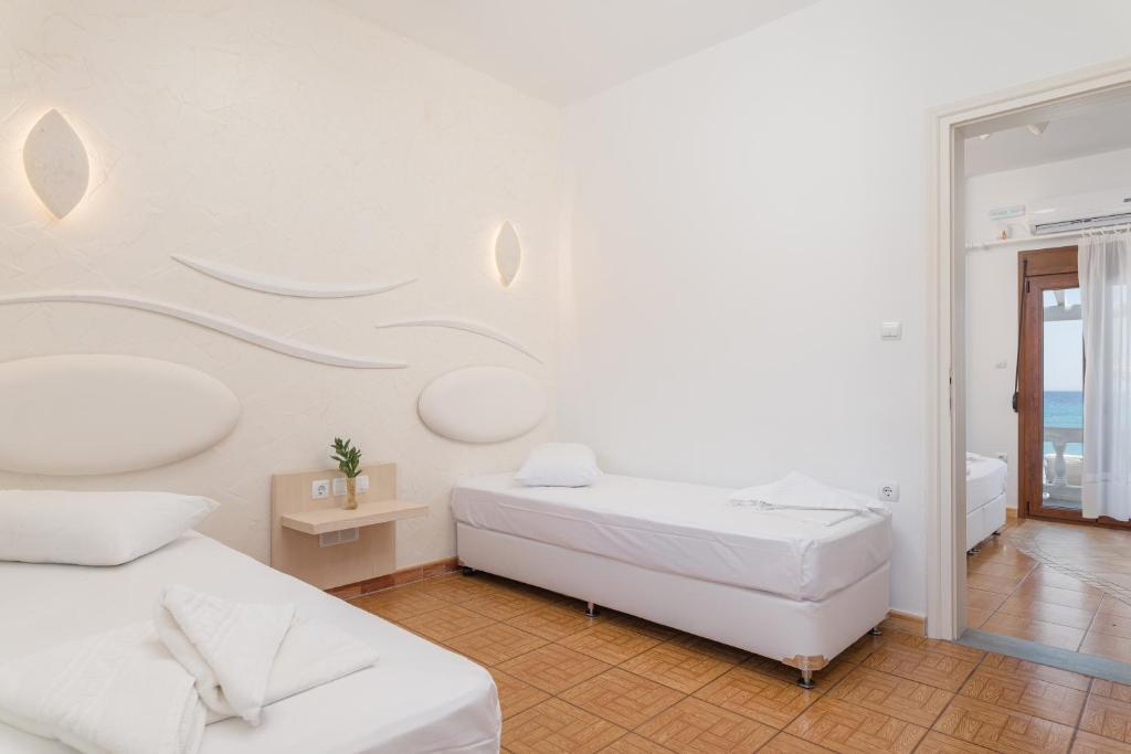 a white room with two beds and a mirror at Kokkari Beach Hotel in Kokkari