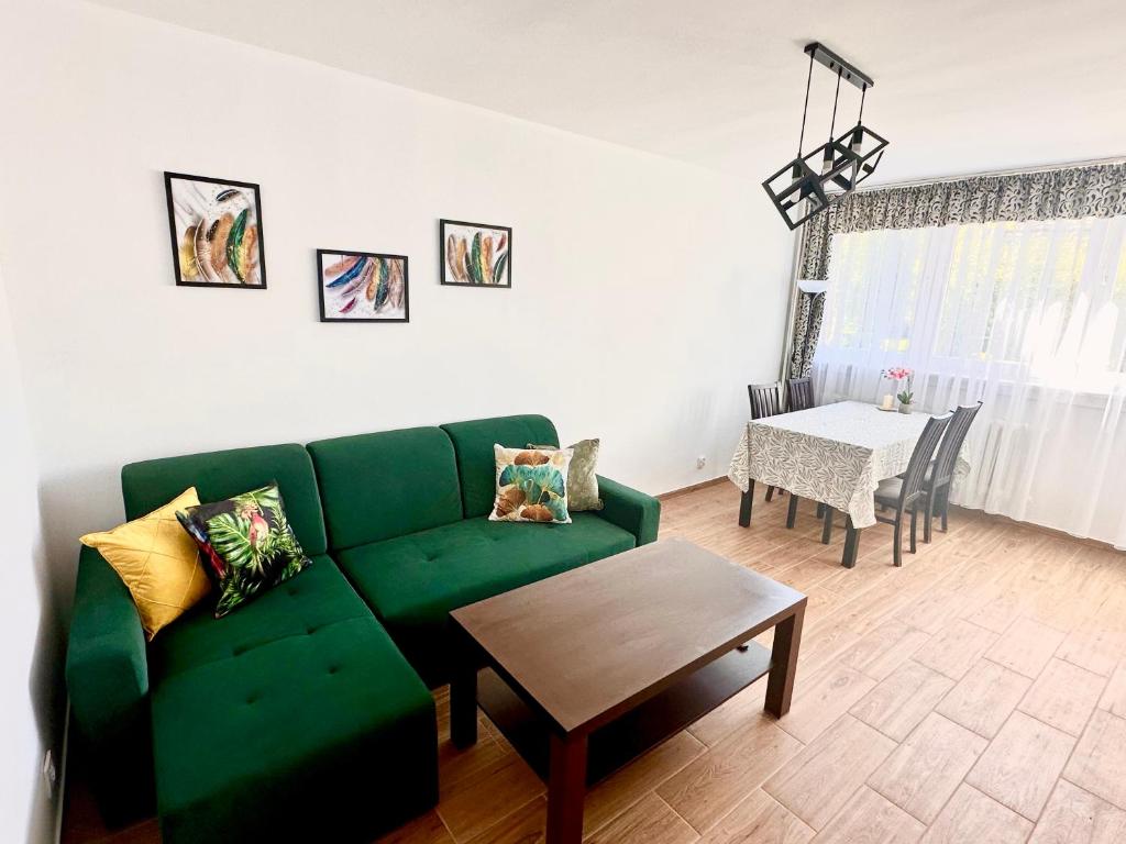 een woonkamer met een groene bank en een tafel bij Roma in Duszniki Zdrój
