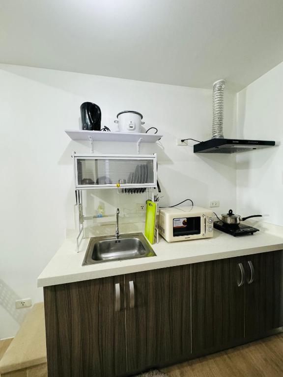 a kitchen with a sink and a microwave at Vinia Infinity Studio 1 Near Malls with WiFi and Netflix in Manila