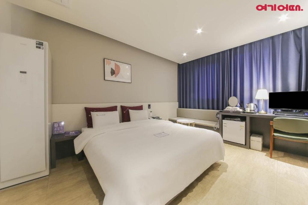 1 dormitorio con 1 cama blanca grande y escritorio en Chungjangro Ilbeonji Boutique Hotel en Gwangju