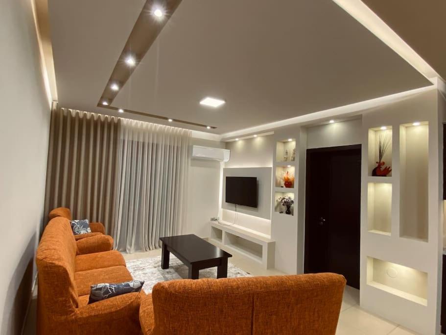 a living room with two orange chairs and a television at Cozy Corner - Apartment in Korça in Korçë