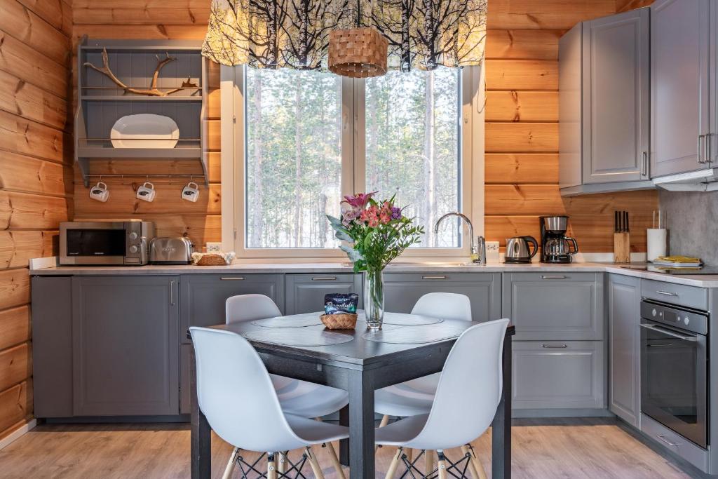 una cocina con una mesa con sillas blancas y una ventana en Arctic Nature Lodge, en Inari