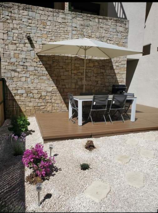 un patio avec une table et un parasol dans l'établissement Duplex T3 avec jardin, bord de mer et parking, à Six-Fours-les-Plages