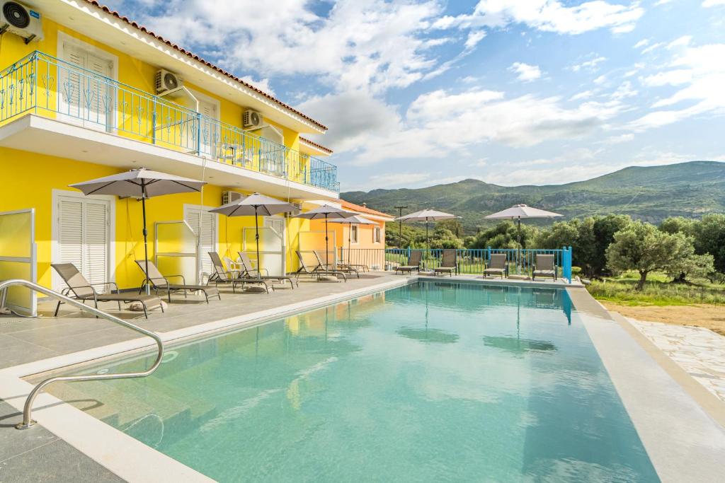 a swimming pool in front of a yellow building with chairs and tables at Anastasia Studios Katelios in Katelios