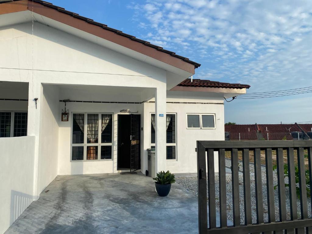 une maison blanche avec une porte noire et une clôture dans l'établissement Rumah 2029, à Masjid Tanah
