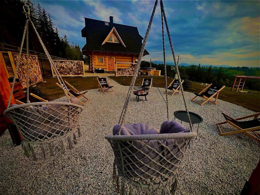 dois baloiços em frente a uma cabana de madeira em Legenda Lasu - drewniany domek w górach, przy stoku narciarskim Kotelnica, Białka Tatrzańska, w pobliżu Term Bania em Groń