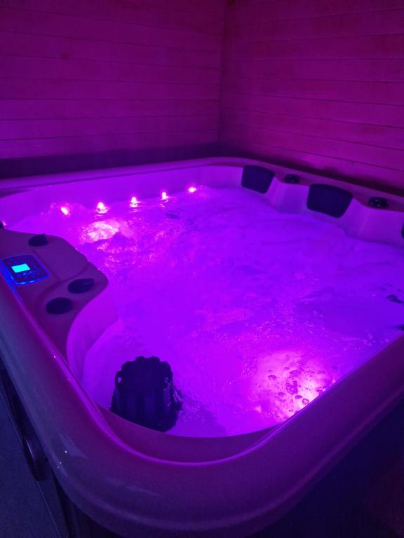 - un bain à remous violet avec des lumières dans la chambre dans l'établissement Chalet bord de l'eau avec spa privatif, à Longpré-les-Corps-Saints