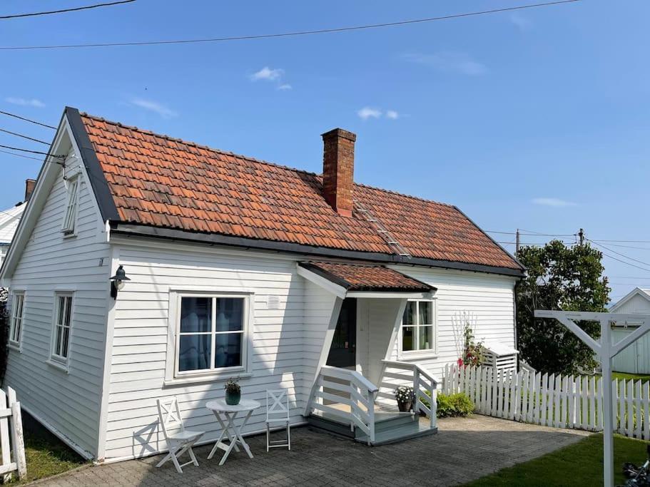 een klein wit huis met twee stoelen en een tafel bij Koselig hus med 4 soverom 7 min gange fra sentrum in Gjøvik