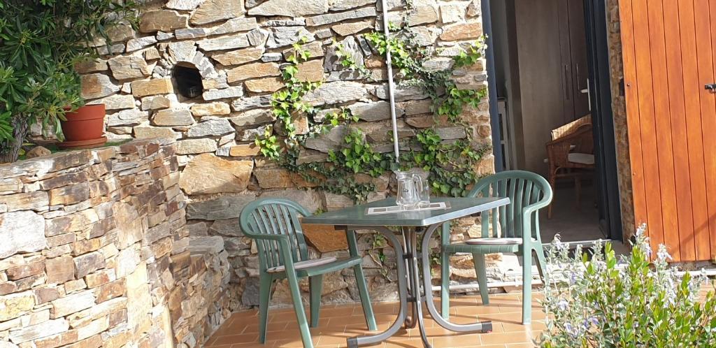 une table et des chaises sur une terrasse avec un mur en pierre dans l'établissement Studio meublé 3 étoiles, au Lavandou