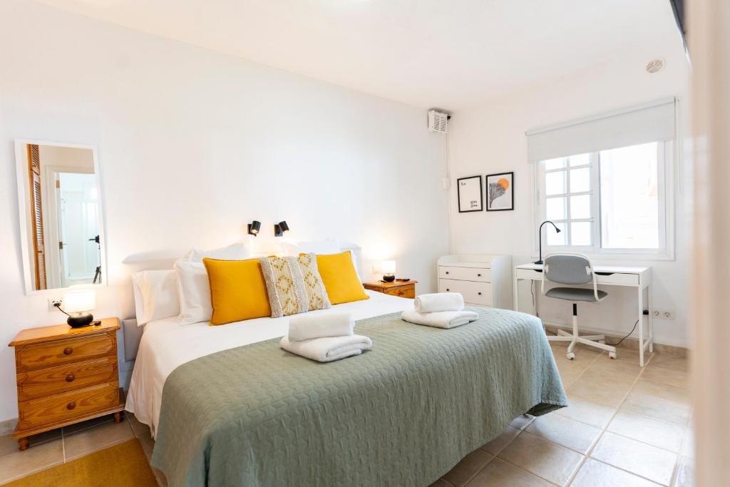 um quarto branco com uma cama grande e almofadas amarelas em Casa El Drago 6 em Breña Baja