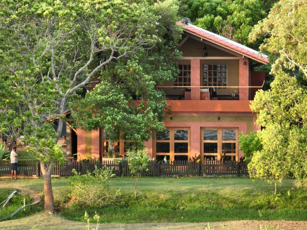 une maison rouge avec des arbres devant elle dans l'établissement Art Yala, à Tissamaharama