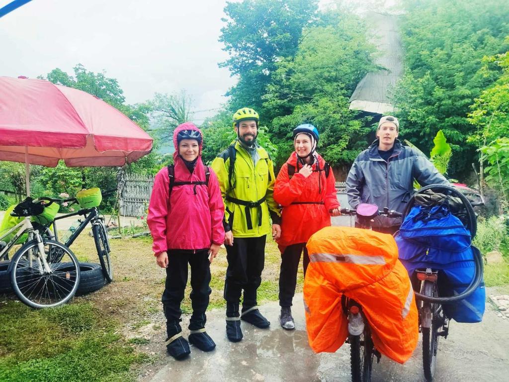 um grupo de pessoas de pé na chuva com suas bicicletas em Grandmother Naziko em Vani
