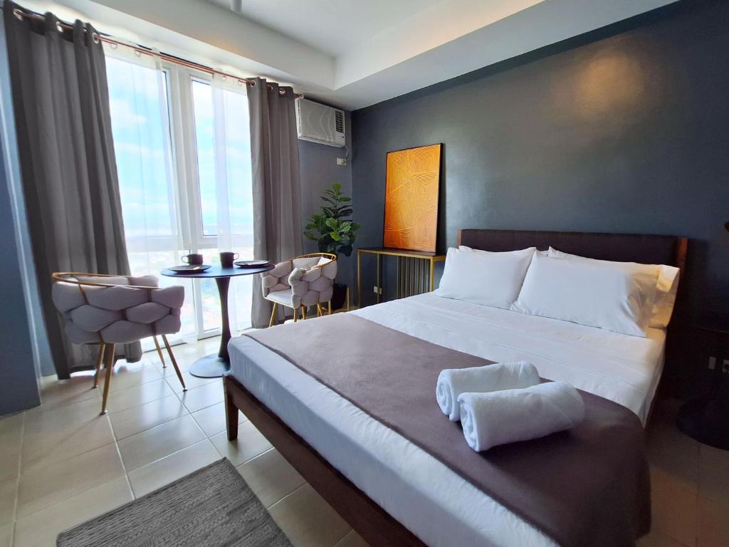 ELUDE Designer Suite Pasig - Prime Location في مانيلا: غرفة نوم بسرير كبير وطاولة مع كراسي