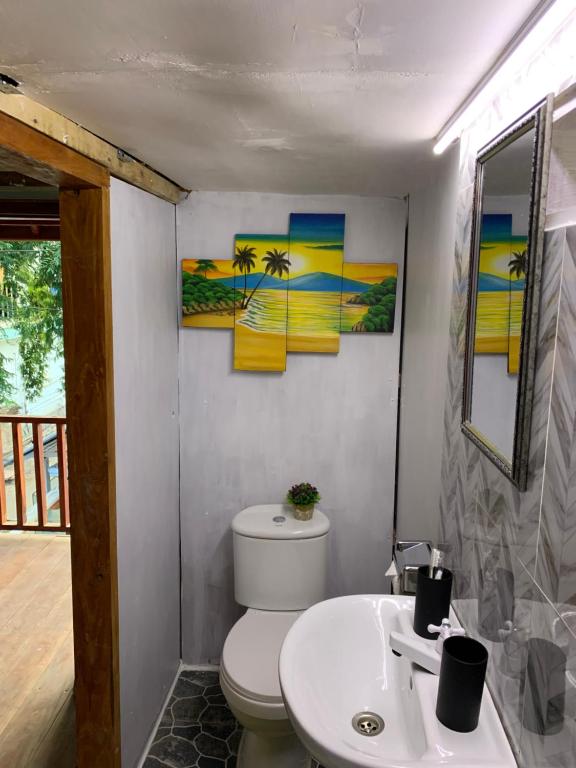 a bathroom with a toilet and a sink and two paintings at Gili Davidoff Upstairs Budget And Deluxe in Gili Trawangan