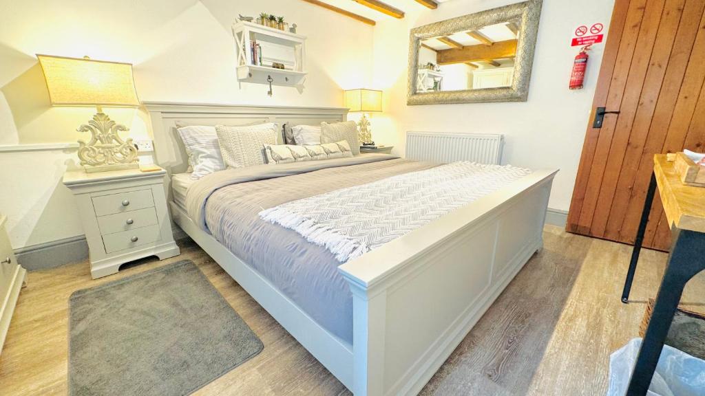 a bedroom with a large white bed and a mirror at Swallow Barn in Penrith