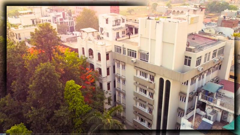 un grand bâtiment blanc avec des arbres devant lui dans l'établissement Hotel MM Continental, à Varanasi