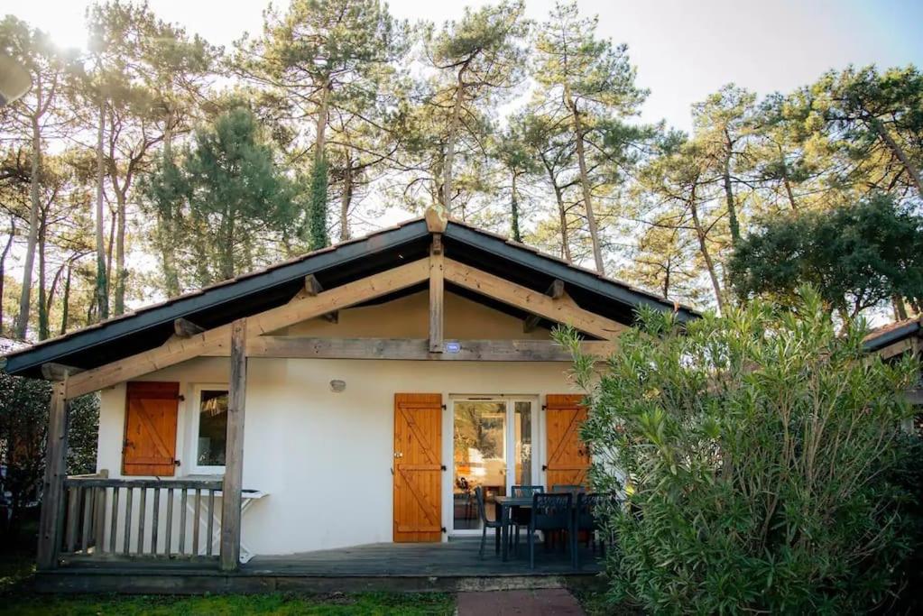 une petite maison blanche avec des portes orange et un porche dans l'établissement maison piscine proche plage, à Ondres