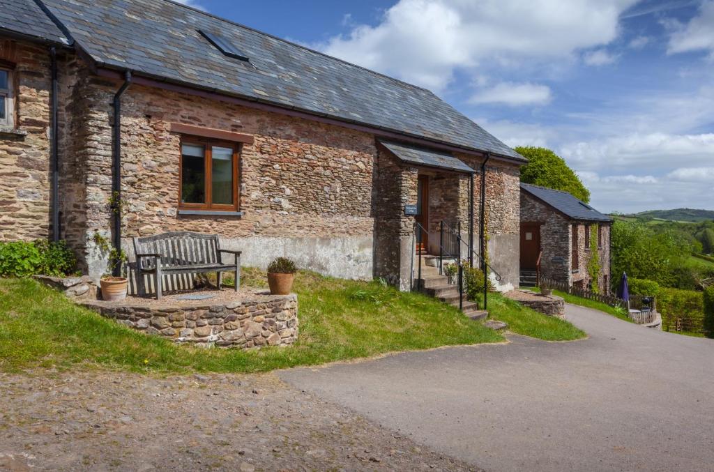 una casa de ladrillo con un banco delante de ella en Harthanger View Cottage, Luxborough en Luxborough