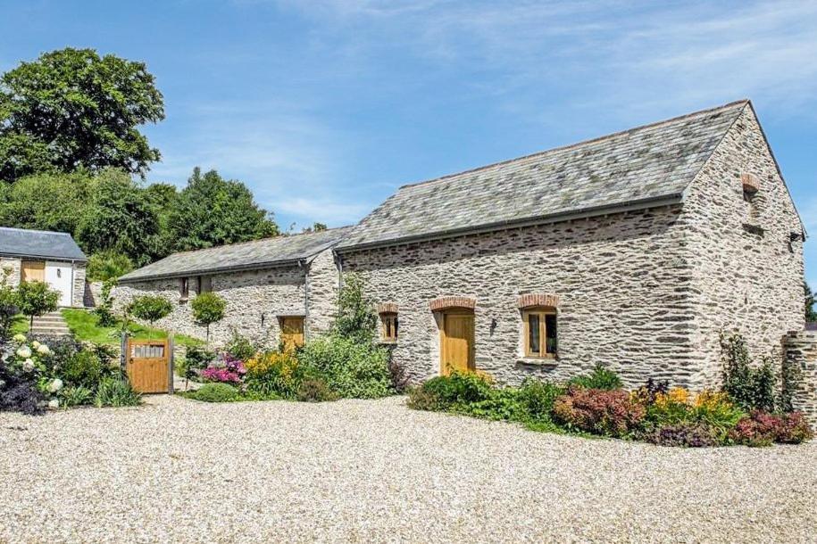 ein altes Steinhaus mit Garten davor in der Unterkunft The Cowshed in Clatworthy