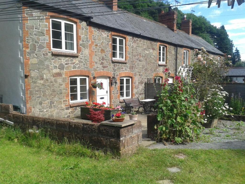 a stone house with flowers in front of it at Magnolia Cottage in Porlock