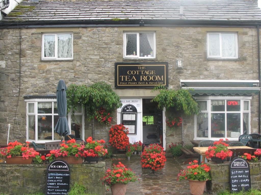 a tea room with flowers in front of a building at The Cottage Tea Room B&B in Kettlewell