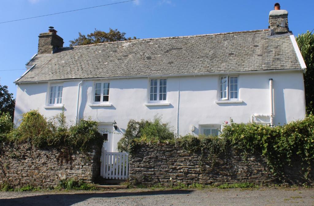 a white house with a stone wall at Old Church House, Brayford in Highbray