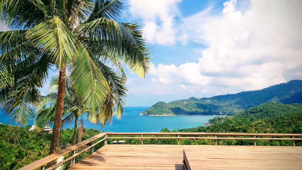 une terrasse en bois avec des palmiers et une vue sur l'océan dans l'établissement Ozone Hill Panoramic Residence Thong Nai Pan Beach, à Thong Nai Pan Noi
