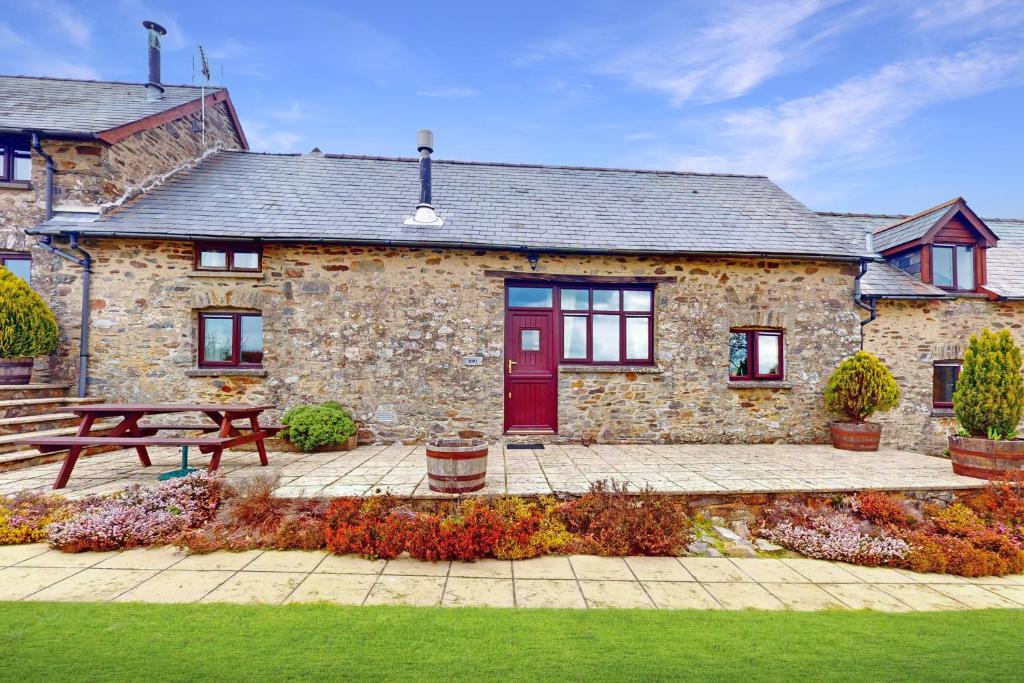 una casa in pietra con una porta rossa e una panchina di Kiri Cottage Hawkridge a Dulverton
